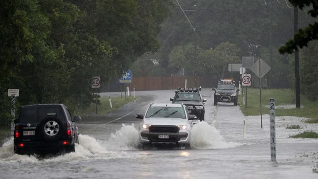 Motorists traverse water across the road at the entrance to Machans Beach. Picture: Stewart McLean