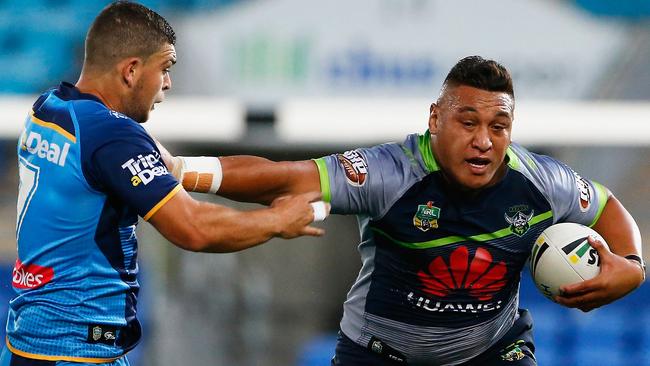 Raiders forward Josh Papalii breaks the tackle of Titans halfback Ashley Taylor.