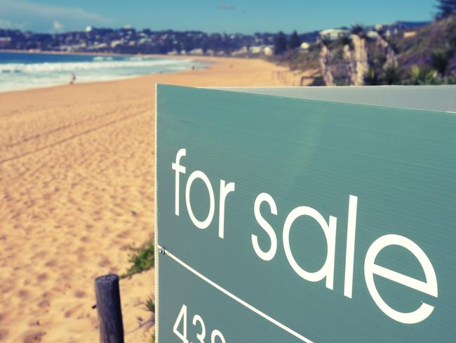 Real estate for sale sign on a beach with waves