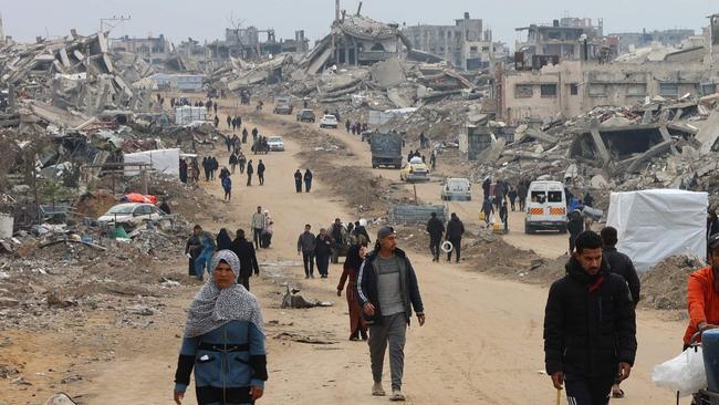 Palestinians walk past collapsed buildings along Saftawi street in Jabalia in the northern Gaza Strip on February 5, 2025 during a ceasefire deal in the war between Israel and Hamas. Palestinian militant group Hamas lashed out on February 5, at President Donald Trump's shock proposal for the United States to take over the Gaza Strip and resettle its people in other countries, seemingly whether they want to leave or not. (Photo by Omar AL-QATTAA / AFP)