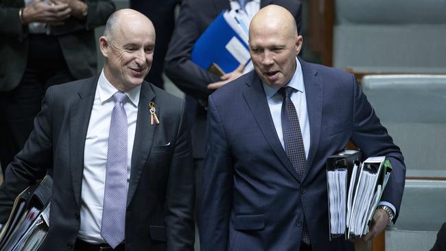 Government ministers Stuart Robert and Peter Dutton share a joke during a rain-affected question time on Monday. Picture: Gary Ramage