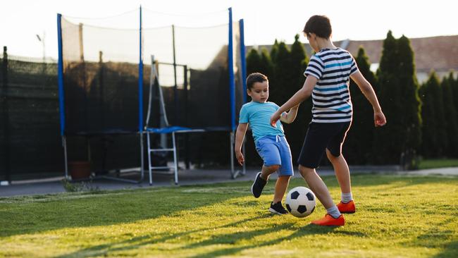 Brothers playing soccer in their backyard