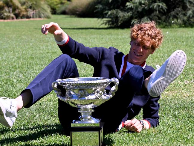 TOPSHOT - Italy's Jannik Sinner makes himself confortable to pose with the Norman Brookes Challenge Cup trophy at the Royal Botanic Gardens following his victory against Russia's Daniil Medvedev in the men's singles final match of the Australian Open tennis tournament in Melbourne on January 29, 2024. (Photo by WILLIAM WEST / AFP) / -- IMAGE RESTRICTED TO EDITORIAL USE - STRICTLY NO COMMERCIAL USE --