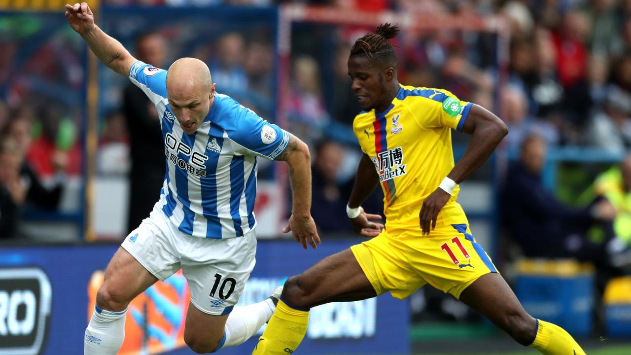 Aaron Mooy of Huddersfield Town is challenged by Wilfried Zaha of Crystal Palace