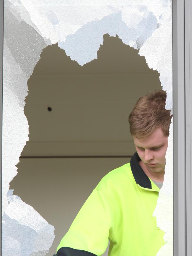 A glass repairman fixes a shot out window at Stephen Dank’s home. Picture: David Crosling