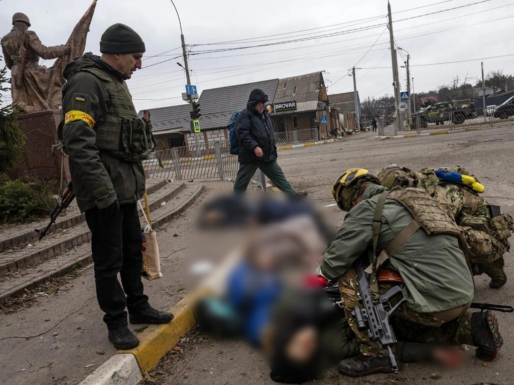 Ukrainian soldiers trying to save the father of a family of four — the only one at that moment who still had a pulse — moments after being hit by a mortar while trying to flee Irpin, near Kyiv. Picture: Lynsey Addario for The New York Times