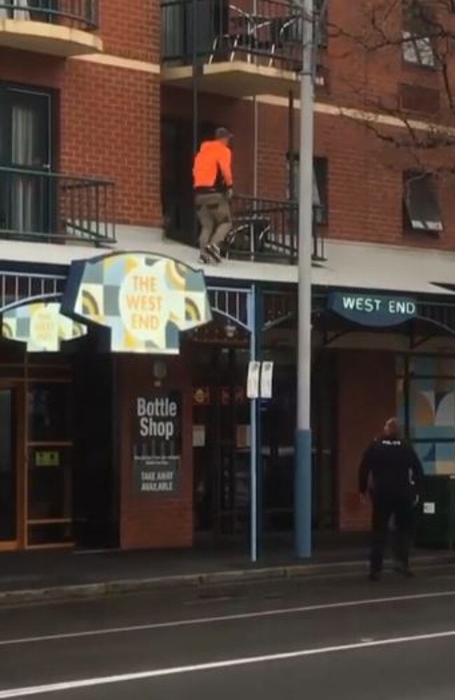 The officer follows him as he walks along the veranda roof. Pictures: ShitAdelaide / Instagram