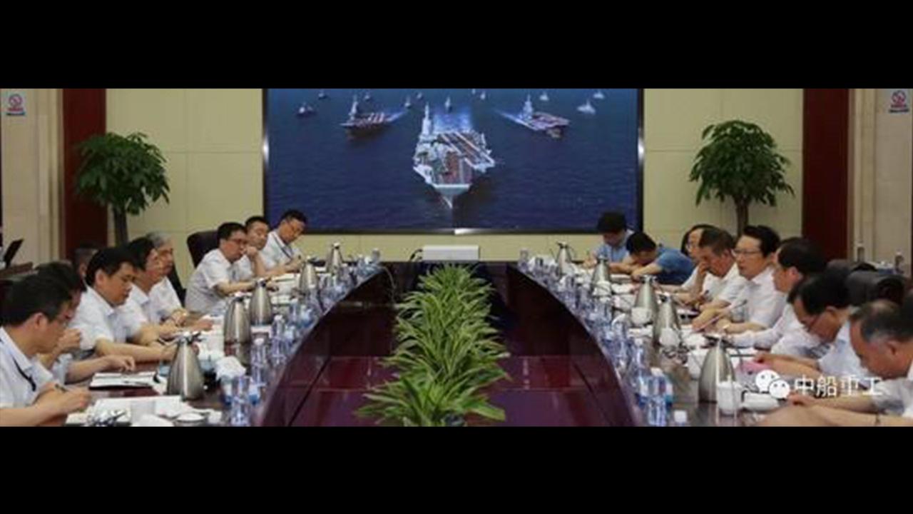 Senior China Shipbuilding Industry Corporation (CSIC) executives attend a function in the company's boardroom, with what appears to be a computer-generated rendering of a new aircraft carrier in the background.