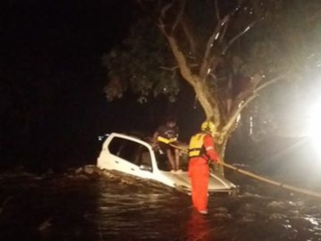 Rescue workers help rescue three people trapped in a tree. PHOTO: NT Police