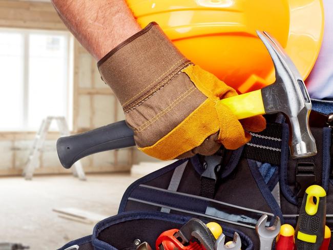 Builder handyman with construction tools. House renovation background.