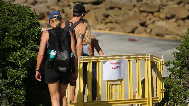 People ignore a sign and enter a closed off section of Clovelly Beach. Picture: Richard Dobson