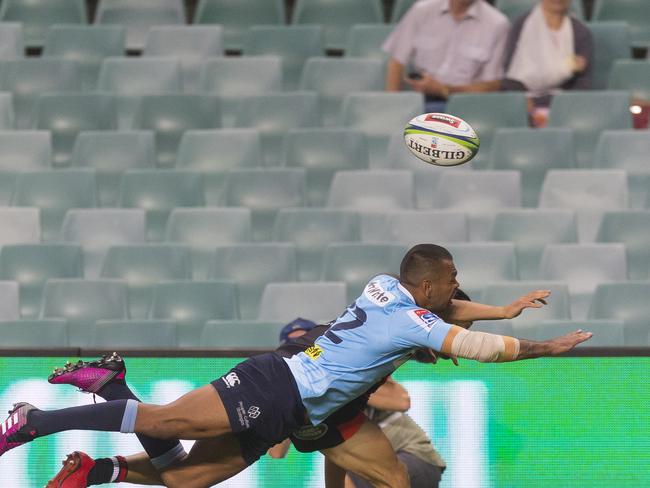 Waratahs star Kurtley Beale dives for a ball against a backdrop of empty seats on Saturday night.