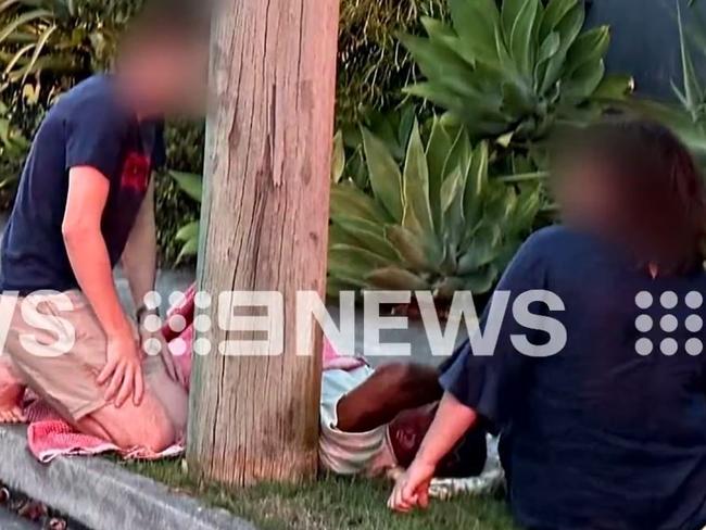 A distraught Ezra Mam lying on a nature strip after the car crash. Picture: 9 News Queensland