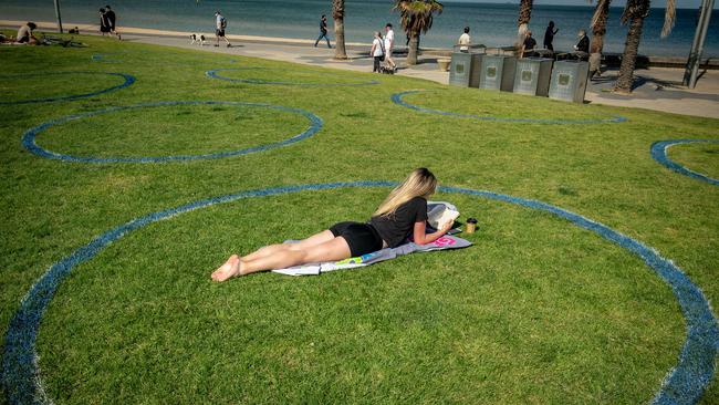 A woman lays on the grass at St Kilda beach.