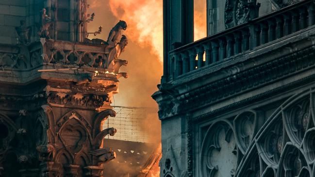 Flames and smoke billow around the gargoyles decorating the roof and sides of the Notre-Dame cathedral in Paris on April 15, 2019.