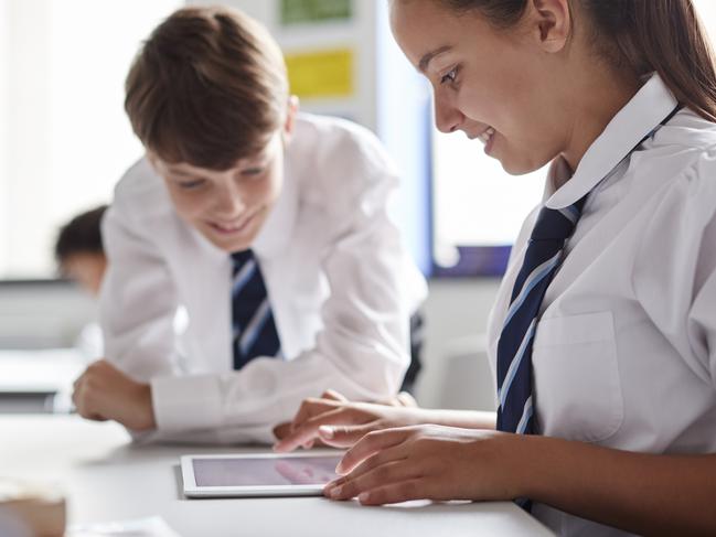 Two High School Students Wearing Uniform Working Together At Desk Using Digital Tablet Picture: Istock