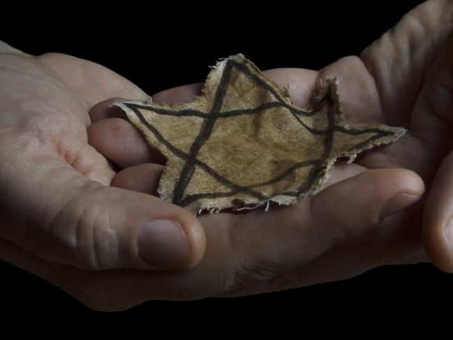 Closeup of a ragged Jewish badge in the hands of a man