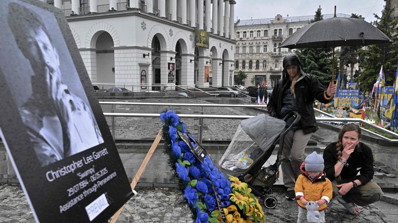 Relatives react at the portrait of 40-year-old British volunteer and EOD technician Christopher Lee Garrett, who died alongside Nic Parsons, during a public memorial in honour of him at Independence Square in Kyiv on May 17, 2025, amid the Russian invasion in Ukraine. Picture: Sergei Supinsky/AFP