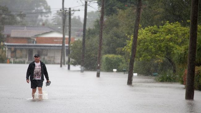 A resident of Macksville on the NSW mid-north coast wades through the rising floodwaters after a week of drenching rain. Picture: Nathan Edwards