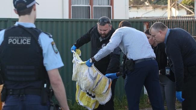 Police officers examine the house and take items from inside as evidence. Picture: David Swift