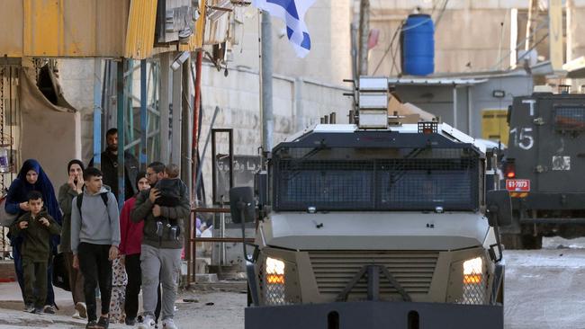 Israeli forces in armoured vehicles drive past Palestinians during a military raid in Jenin, in the occupied West Bank, on Tuesday. Picture: AFP