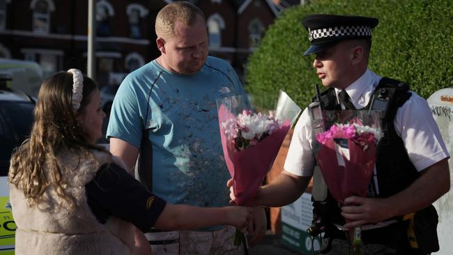 A police officer receives flowers to lay at the scene of the multiple stabbing attack. Picture: Getty Images.