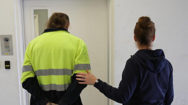 One of the men arrested by police during the raids is led away. Picture: NSW Police