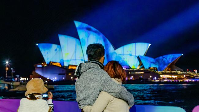 People watch the sails of the Sydney Opera House illuminated with artworks by the late Australian artist John Olsen at the start of the Vivid Sydney festival. Picture: Getty Images