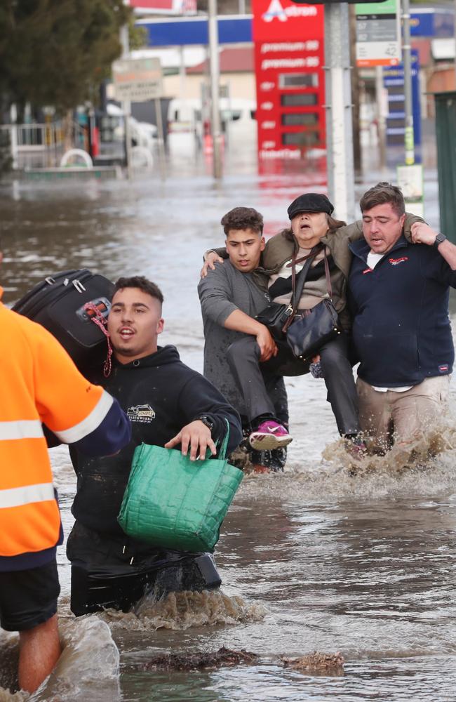 Here, locals have been pictured helping each other navigate the floodwaters. Picture: NCA NewsWire / David Crosling.