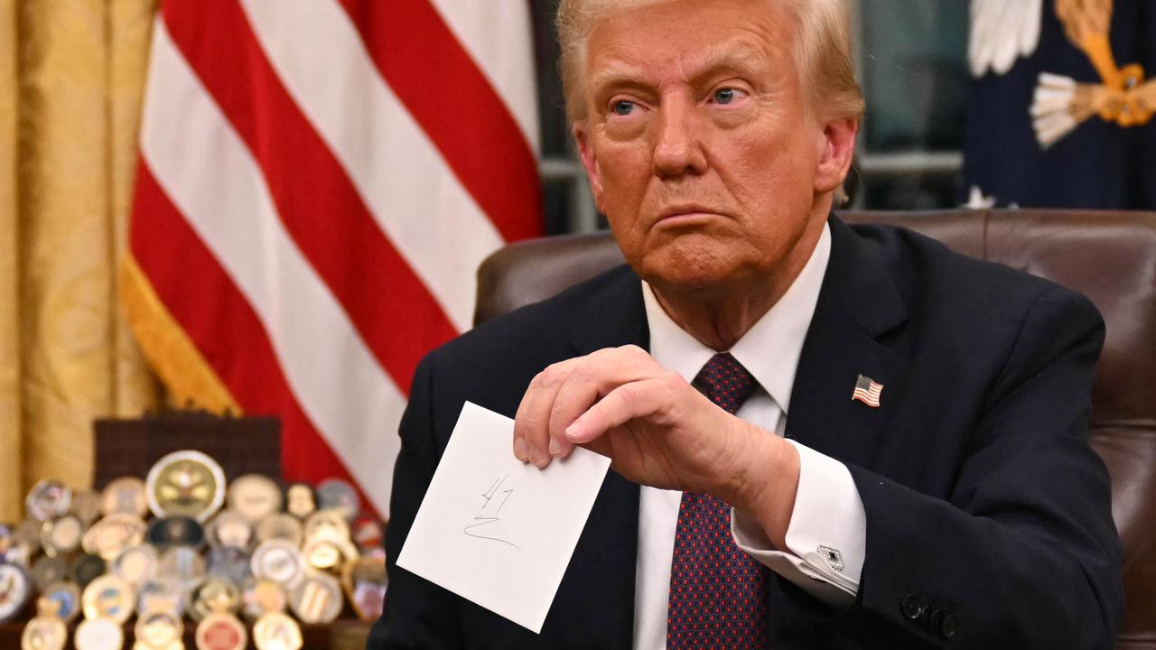 Mr Trump holds up the letter from Mr Biden, in the Oval Office, for reporters. Picture: Jim Watson/AFP