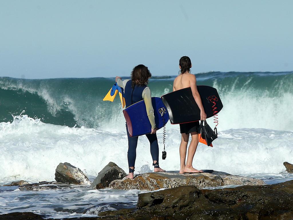 Boogie boarders hesitate to tackle the massive swell pounding the Newcastle coastline. Picture: Peter Lorimer