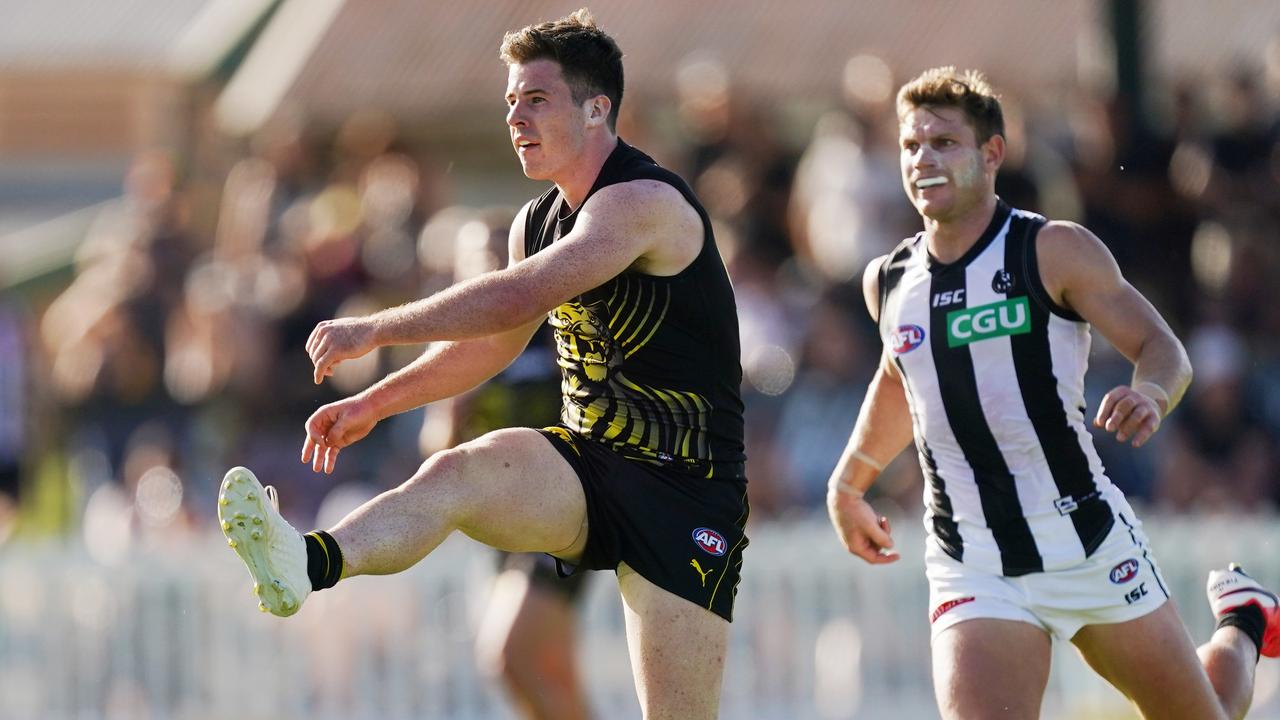 Jack Higgins gets a kick away as Taylor Adams gives chase. Picture: AAP