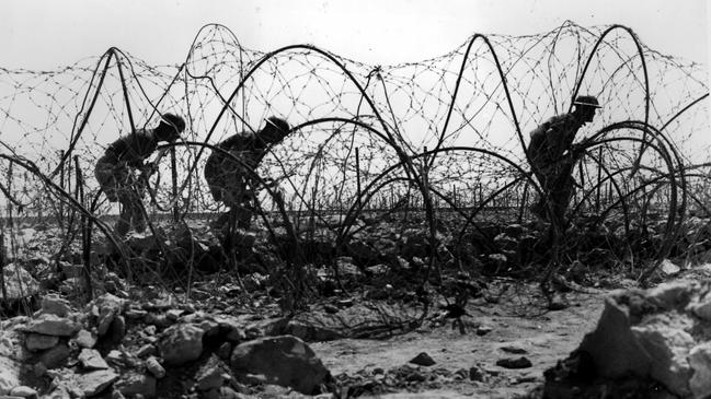 AIF soldiers of 'C' Company, 2/13 Battalion going out through barbed wire on the outer defences of the Tobruk area. Picture:  Australian War Memorial.