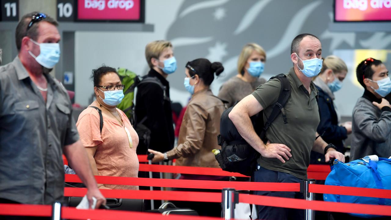 Travellers queue after arriving at the Brisbane Airport with masks on. Picture: NCA NewsWire / John Gass