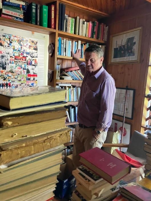 Rob Schwarten looks over the book collection which fills a room at his home.