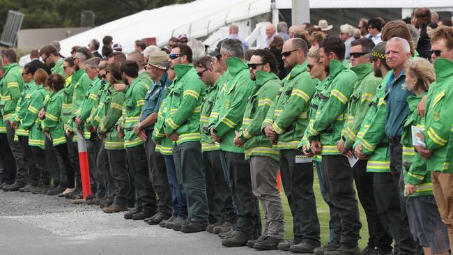 A guard of honour of Forestry and Fire Management workers lines the road as Bill Slade’s hearse departs. Picture: AAP