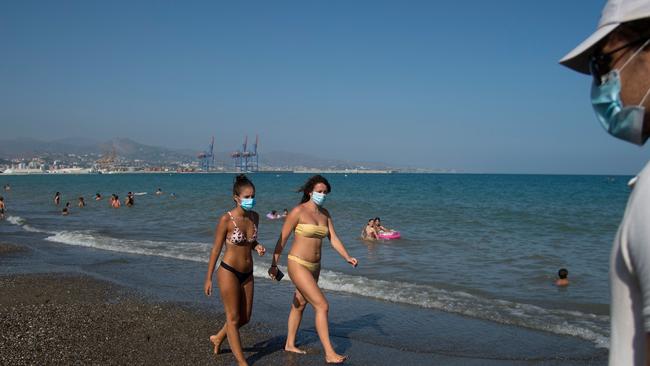 People wearing face masks while walking along La Misericordia Beach in Malaga, Spain. Picture: AFP