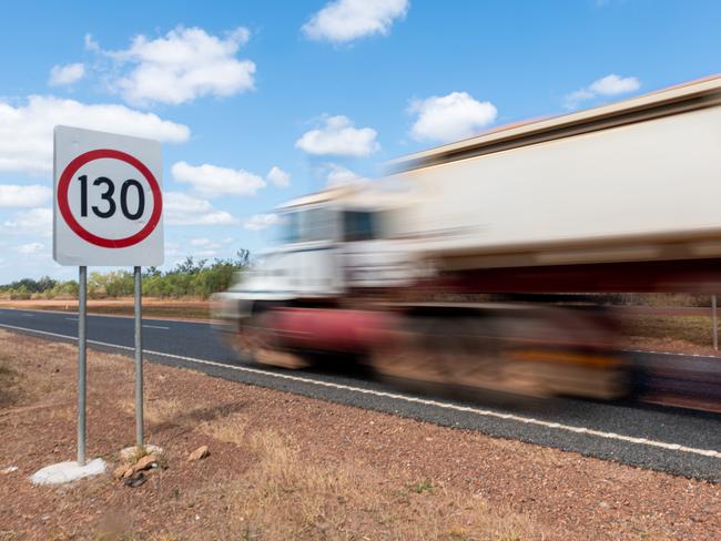 Cars and road trains pass a road sign announcing a new speed limit of 130kmh on the Stuart Highway.Picture: Che Chorley