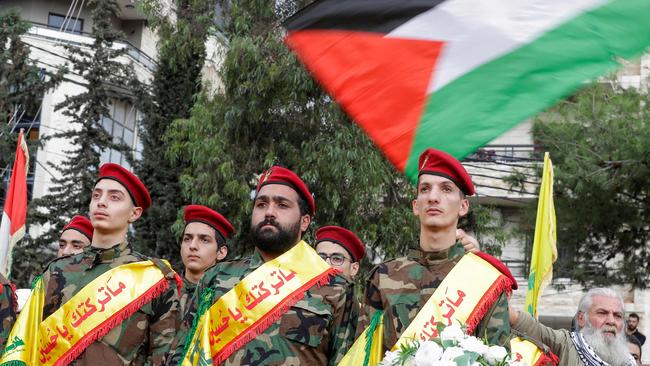 A man waves the Palestinian flag during the funeral of three Hezbollah fighters