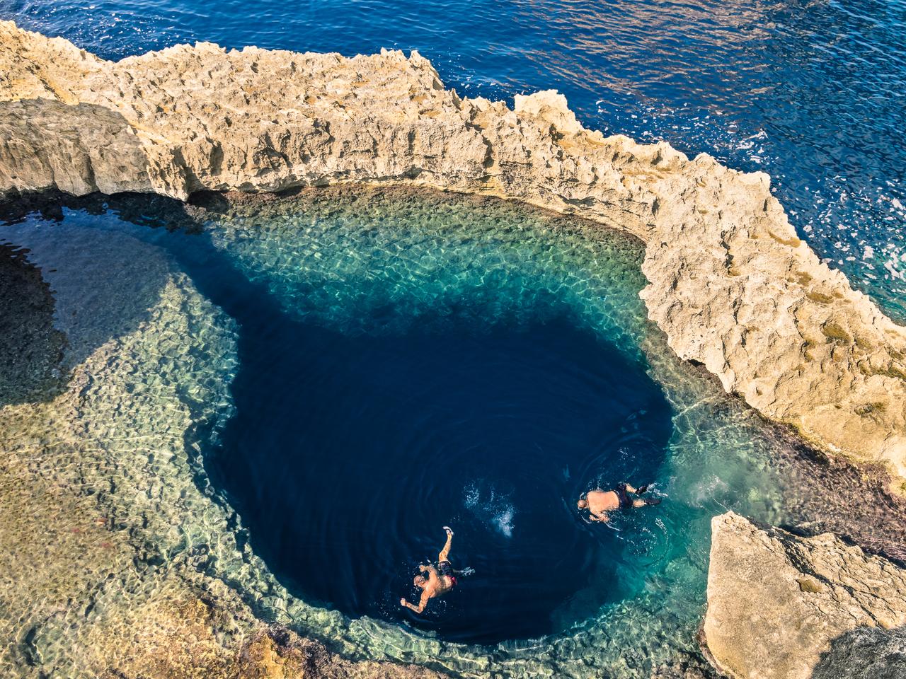Deep blue hole at the world famous Azure Window in Gozo island - Mediterranean nature wonder in the beautiful Malta - Unrecognizable scuba divers swimming to adventure water cave
