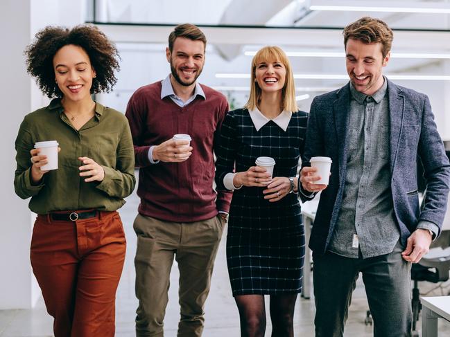 CAREERS: surprise your colleagues with a coffee to improve workplace happiness. Picture: iStockGroup of diverse coworkers walking through a corridor in an office, holding paper cups