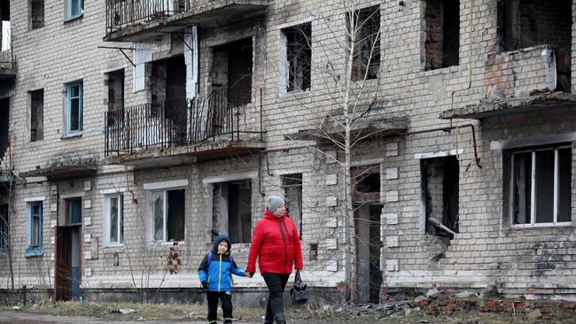 A woman and boy walk past a destroyed building in the small town of Krasnogorivka, in the Donetsk region of Ukraine. Picture: AFP