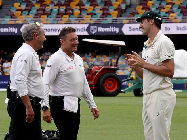 Australiaâs captain Pat Cummins (R) talks with the umpires during a rain delay on day three of the third cricket Test match between Australia and India at The Gabba in Brisbane on December 16, 2024. (Photo by DAVID GRAY / AFP) / -- IMAGE RESTRICTED TO EDITORIAL USE - STRICTLY NO COMMERCIAL USE --