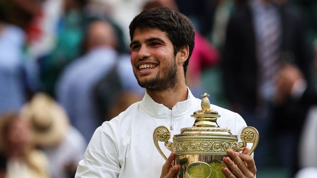 Spain's Carlos Alcaraz smiles as he holds the winner's trophy after beating Serbia's Novak Djokovic during their men's singles final tennis match on the last day of the 2023 Wimbledon Championships at The All England Tennis Club in Wimbledon, southwest London, on July 16, 2023. (Photo by Adrian DENNIS / AFP) / RESTRICTED TO EDITORIAL USE