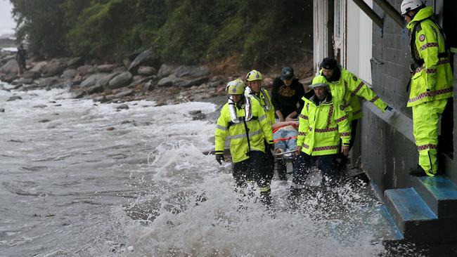 An ambulance crew battles the incoming tide to rescue a man from the rocks at The Haven, Terrigal, during the massive storm that hit the Central Coast on Sunday. Picture: Troy Snook