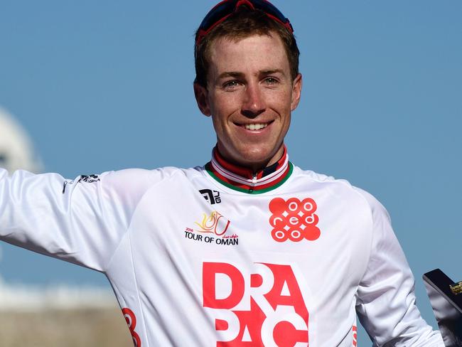 Australian Brendan Canty of Wanty-Groupe Gobert raises his arm during the victory ceremony after the 6th and last stage of the 7th cycling Tour of Oman between Muscat and Mutrah Corniche on February 21, 2016. Vincenzo Nibali kept the red jersey after winning the Tour. / AFP / ERIC FEFERBERG