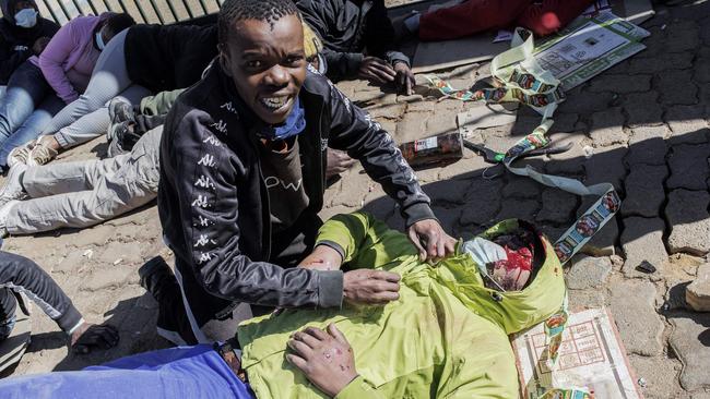 A suspected looter begs for help for his brother, allegedly wounded by two rubber bullets shouted by security guards in Soweto. Picture; AFP.