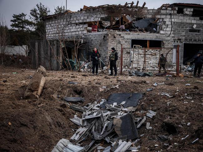 Police officers and residents stand next to a shell crater in front of a house damaged by recent shelling on the outskirts of Kyiv. Picture: Dimitar Dilkoff / AFP)