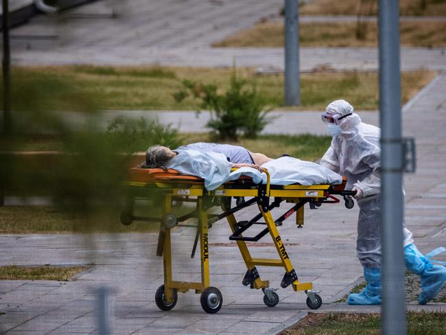 TOPSHOT - A medic escorts a woman into a hospital where patients infected with the COVID-19 novel coronavirus are being treated in the settlement of Kommunarka outside Moscow on June 30, 2021. - Russia on June 30, reported 669 coronavirus deaths over the past 24 hours, a record number of fatalities for the second day in a row, according to a government tally. The country is grappling with a spike of infections spurred by the highly infectious Delta variant, and President Vladimir Putin was expected to address the surge in cases during a televised phone-in session with Russians set to begin later Wednesday. (Photo by Dimitar DILKOFF / AFP)