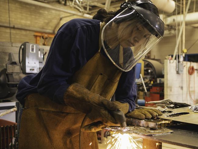 A young teenage high school female is practicing her welding skills while at school. She is working in her high school shop class. Image taken on the Navajo Reservation, Utah, USA.